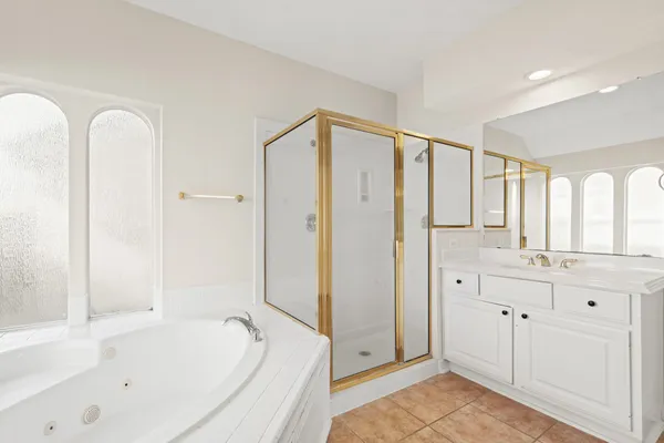 a bathroom with a tub a sink and a large mirror