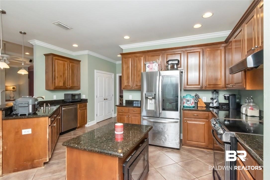 7170 Pierson Drive Mobile, AL 36619 - Photo 10 of 29 Kitchen with stainless steel appliances, a kitchen island, light tile patterned floors, dark stone countertops, and pendant lighting