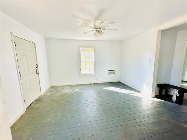 an empty room with wooden floor cabinet and windows