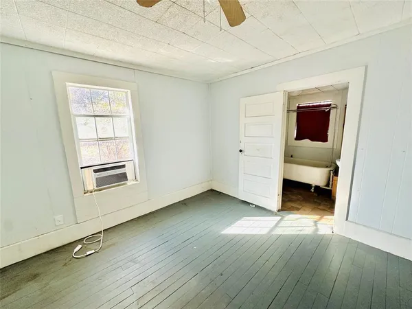 an empty room with wooden floor closet and windows