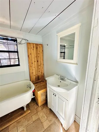 a bathroom with a sink a bathtub and next to a window