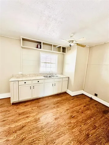 a view of a kitchen with white cabinets and wooden floor