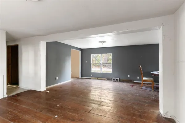 a view of an empty room with window and wooden floor