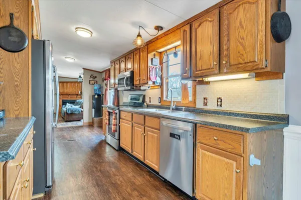 a kitchen with stainless steel appliances granite countertop a refrigerator a sink dishwasher and white cabinets with wooden floor