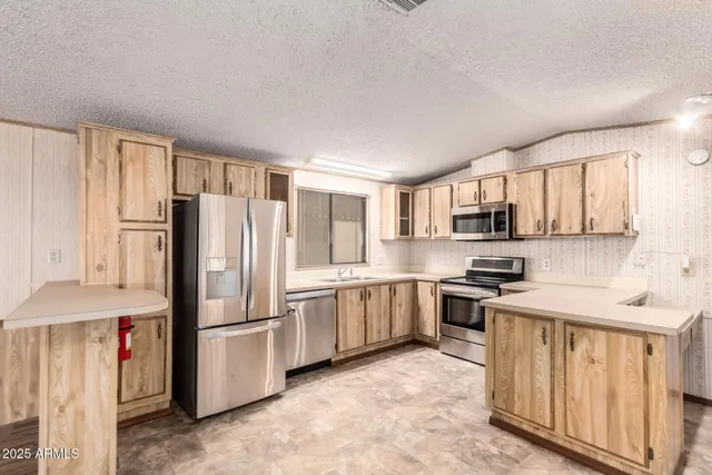 a kitchen with stainless steel appliances granite countertop a refrigerator a stove and a sink