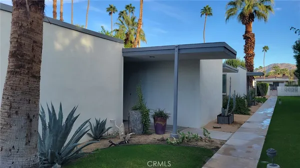 a view of a house with a yard and potted plants