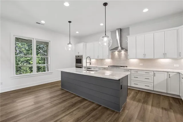 a kitchen with stainless steel appliances granite countertop a sink a stove and a wooden floors