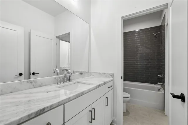 a bathroom with a granite countertop toilet sink and mirror