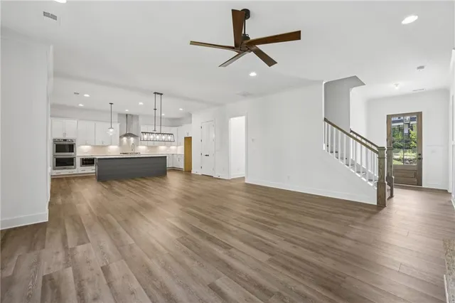 a kitchen with granite countertop a stove a sink and white cabinets with wooden floor