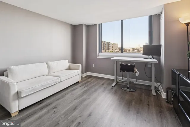 a living room with furniture a window and wooden floor