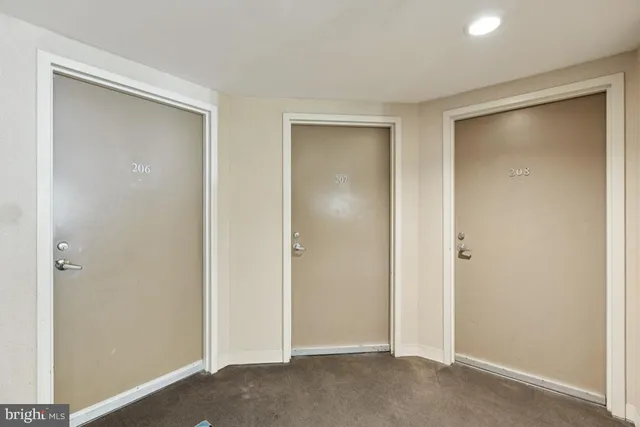 a view of an empty room with closet and wooden door