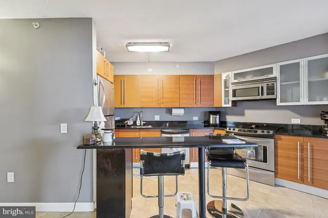 a kitchen with stainless steel appliances granite countertop a stove a sink dishwasher and a refrigerator with wooden floor