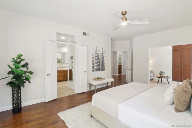 a spacious bedroom with a large bed a chandelier and a potted plant