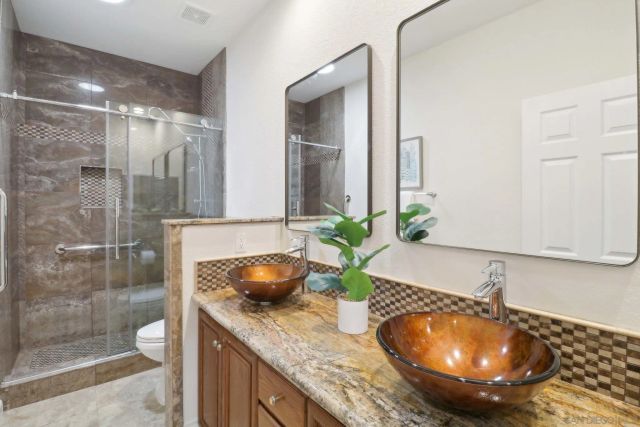 a bathroom with a granite countertop sink a mirror and shower
