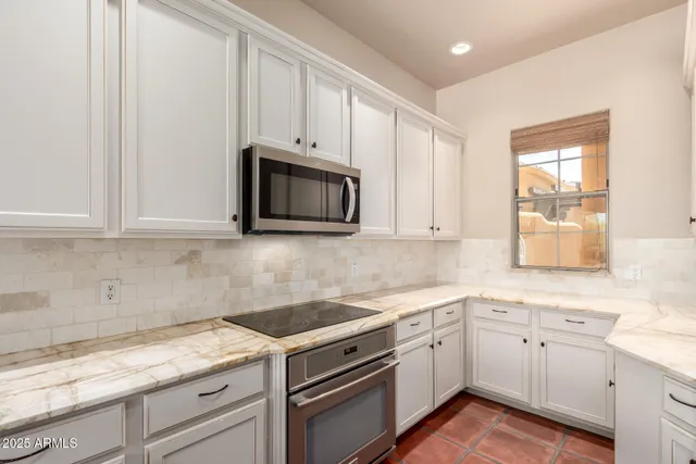 a kitchen with granite countertop white cabinets white stainless steel appliances and a sink