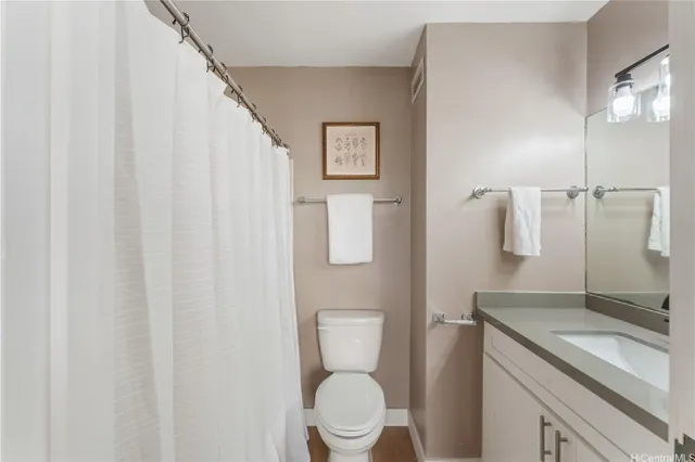 a bathroom with a granite countertop sink toilet and mirror
