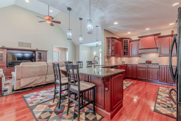 a kitchen with stainless steel appliances kitchen island granite countertop a table chairs and a refrigerator