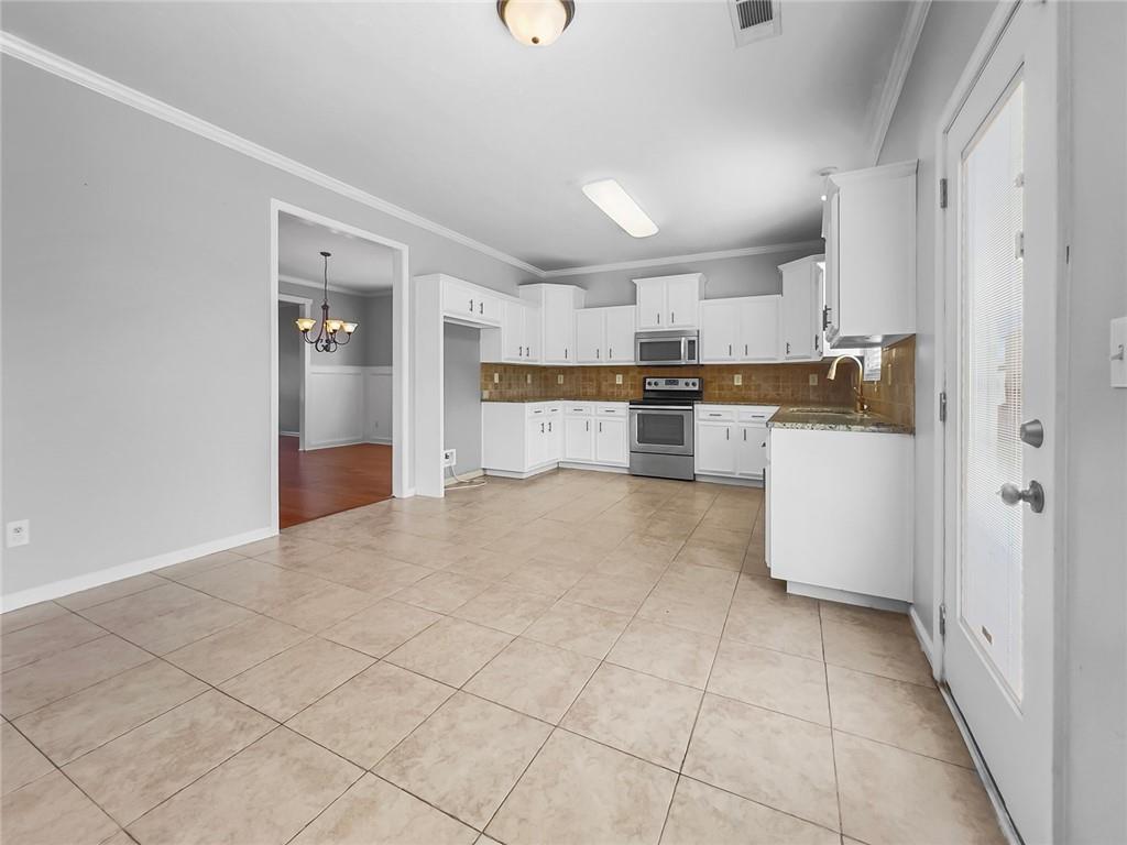 6 Pebblebrook Lane Fort Mitchell, AL 36856 - Photo 7 of 48 Kitchen featuring decorative backsplash, ornamental molding, a chandelier, stainless steel appliances, and light tile patterned flooring
