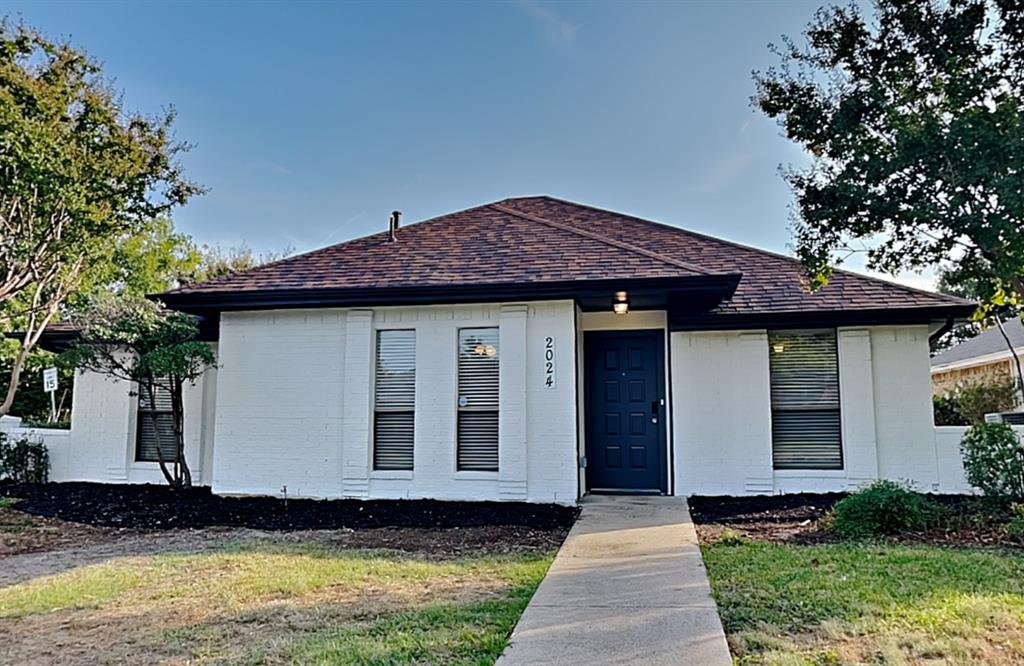 View of front of home with roof with shingles, brick siding, and a front lawn