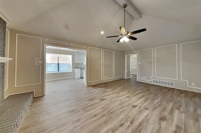 a view of an empty room with wooden floor and a ceiling fan