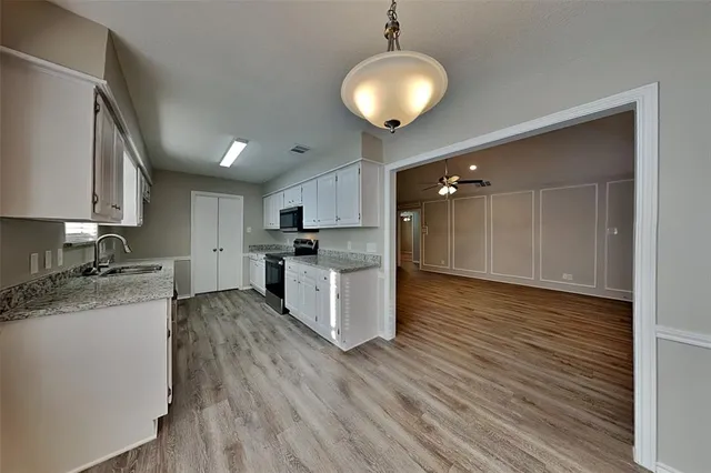 a large kitchen with cabinets wooden floor and stainless steel appliances