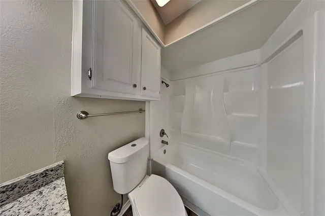 a white toilet sitting next to a bath tub