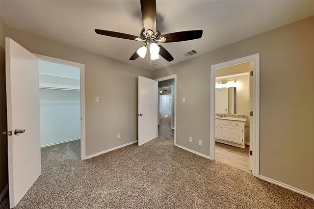 a view of an empty room with window and chandelier fan