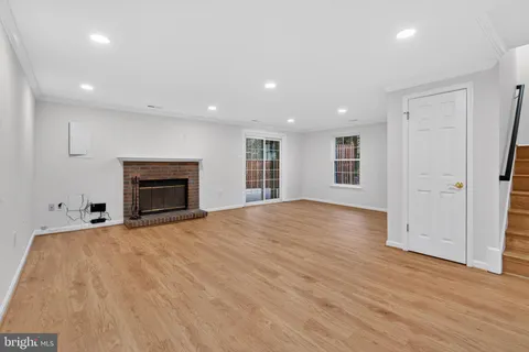 an empty room with wooden floor fireplace and windows