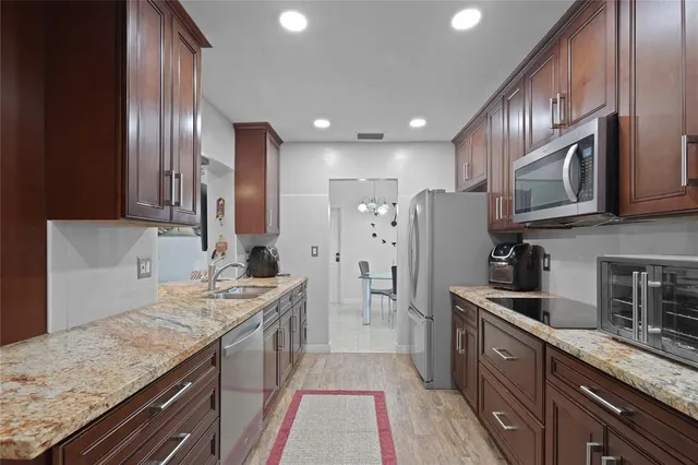 a kitchen with stainless steel appliances granite countertop granite countertop a sink a stove refrigerator and cabinets