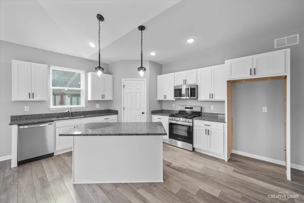 a kitchen with kitchen island granite countertop a stove a sink and a chandelier