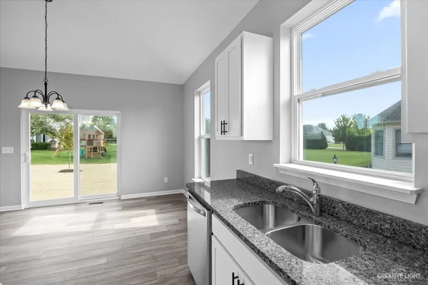 a kitchen with granite countertop a stove a sink and a refrigerator