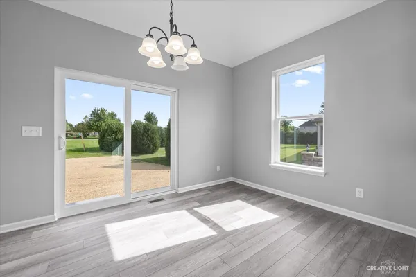 an empty room with wooden floor ceiling fan and windows