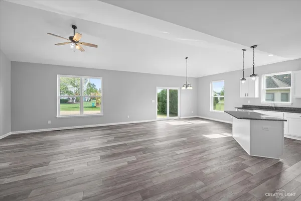 a large kitchen with stainless steel appliances granite countertop a stove a sink a refrigerator and white cabinets with wooden floor