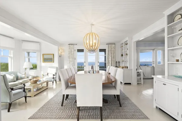 a living room with dining table couches a fireplace and kitchen view