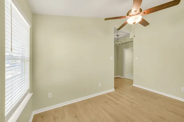 an empty room with a window and a fan