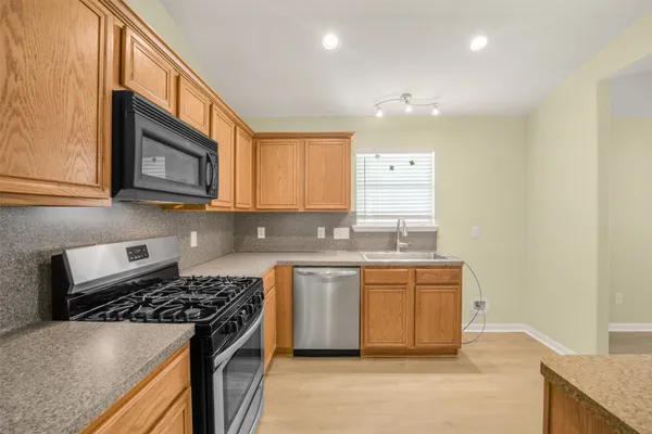 a kitchen with stainless steel appliances granite countertop a stove a sink and a microwave