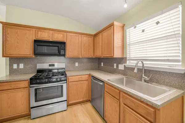 a kitchen with granite countertop a sink cabinets and stainless steel appliances