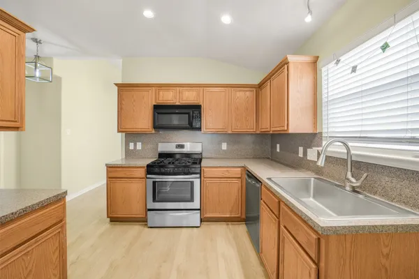 a kitchen with stainless steel appliances granite countertop a sink stove and refrigerator