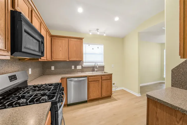 a kitchen with stainless steel appliances granite countertop a stove a sink and a microwave