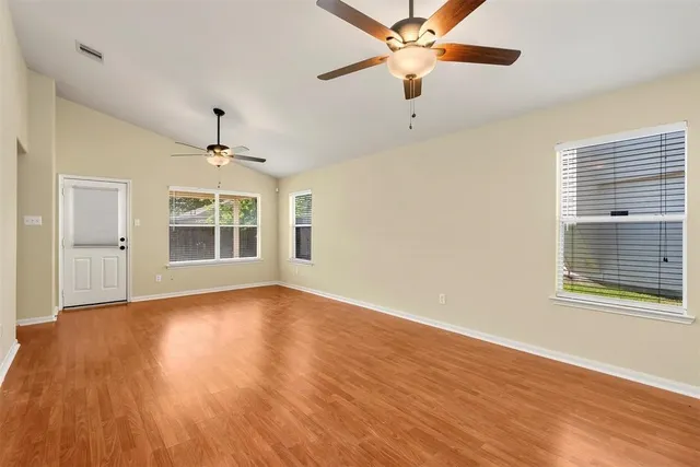 a view of an empty room with a window and wooden floor