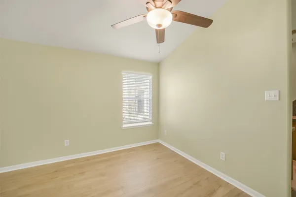 an empty room with a window and a fan