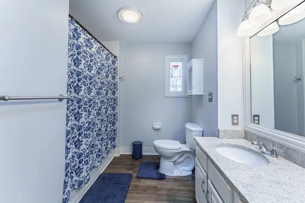 a bathroom with a granite countertop toilet a sink and a mirror
