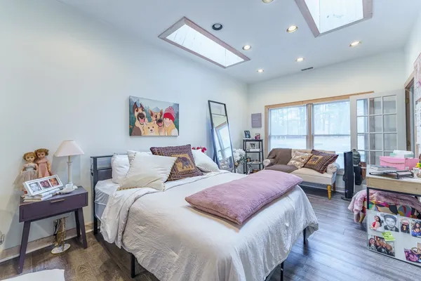 a spacious bedroom with a bed a couch and a dresser next to a window