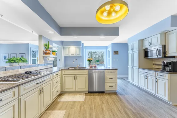 a large kitchen with stainless steel appliances granite countertop a stove and a wooden floors