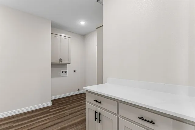 a kitchen with white cabinets and wooden floor