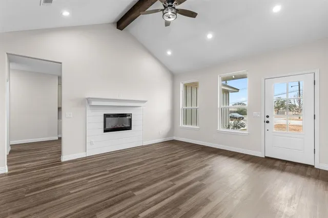 a view of an empty room with a window and wooden floor