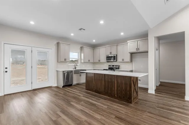 a kitchen with a sink wooden floor stainless steel appliances and cabinets