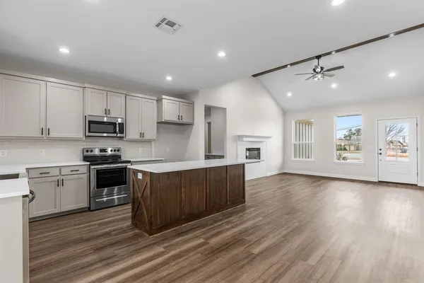 a large kitchen with stainless steel appliances granite countertop a stove a sink dishwasher and a refrigerator with wooden floor