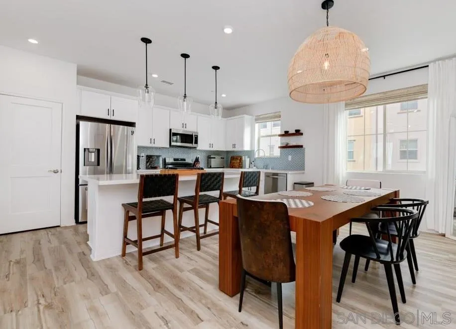a dining area with stainless steel appliances kitchen island a table chairs and a refrigerator
