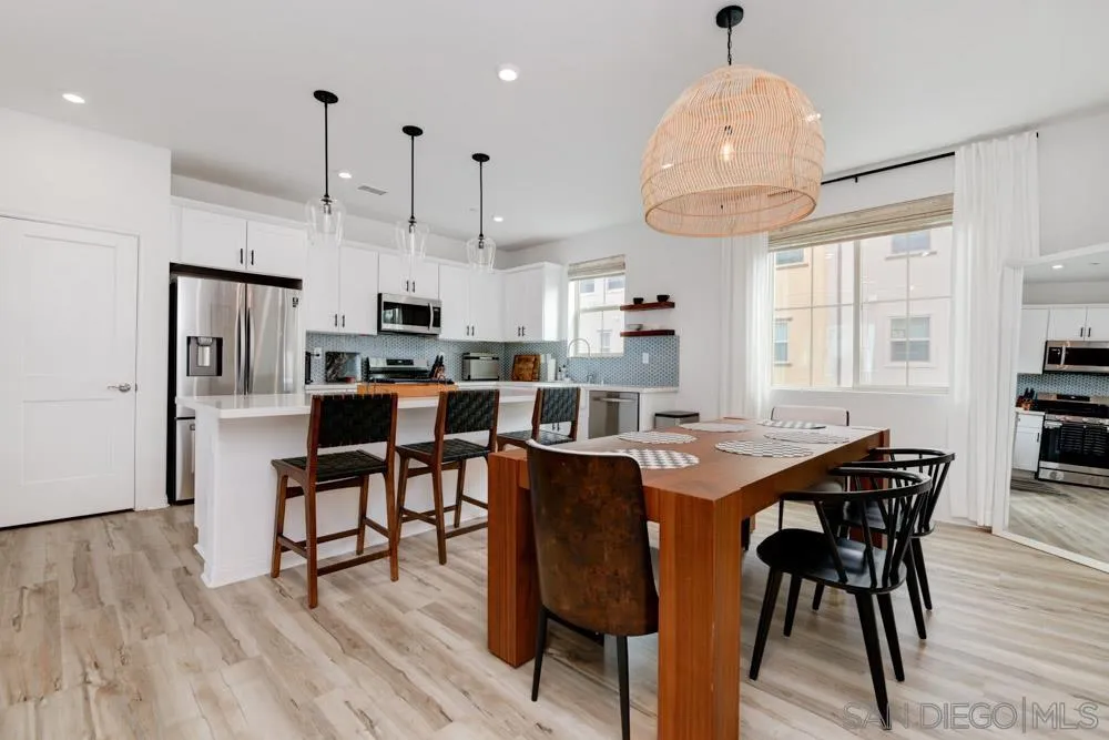 1643 Fig Tree Way Oceanside, CA 92056 - Photo 3 of 29 a kitchen with stainless steel appliances granite countertop a stove a refrigerator a kitchen island a dining table and chairs with wooden floor